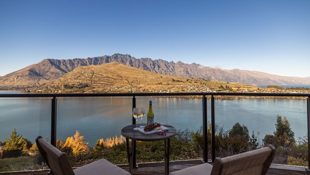 A balcony with a table, two chairs, a bottle of wine, and a glass. - Sunrise Retreat - lake and mountain views (Queenstown)