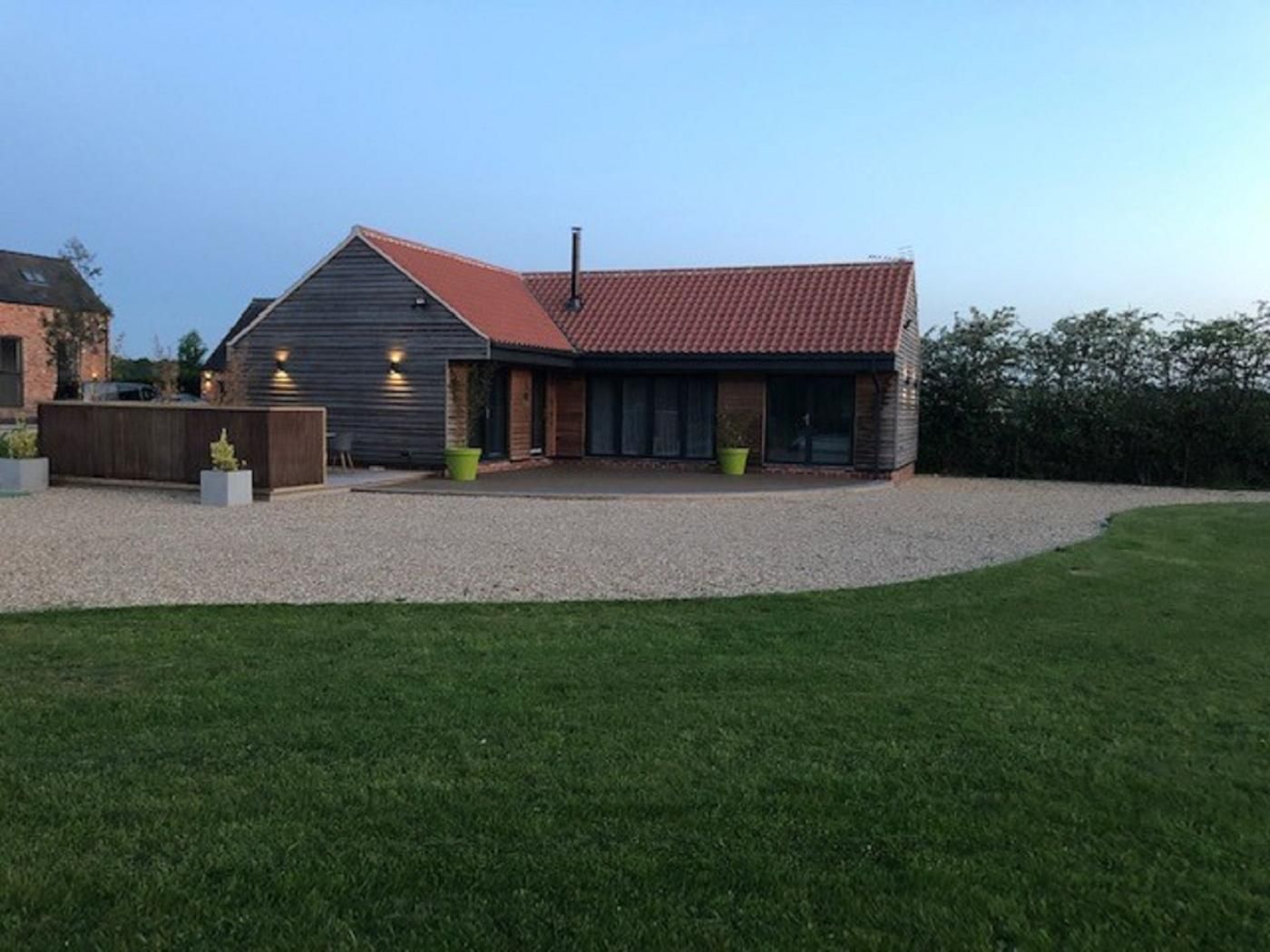 A modern building with a gravel driveway, a covered patio area, and a grassy lawn.