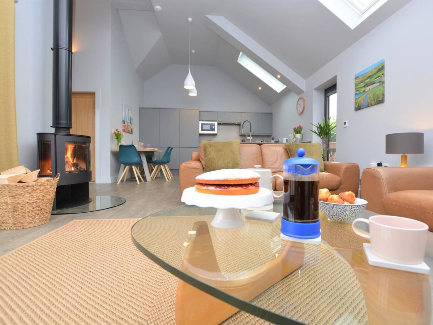 Een moderne woonkamer met een open haard, een eethoek en een keuken op de achtergrond.