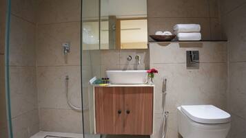 A modern bathroom with a glass-enclosed shower, a wooden cabinet, a white sink, and a toilet.