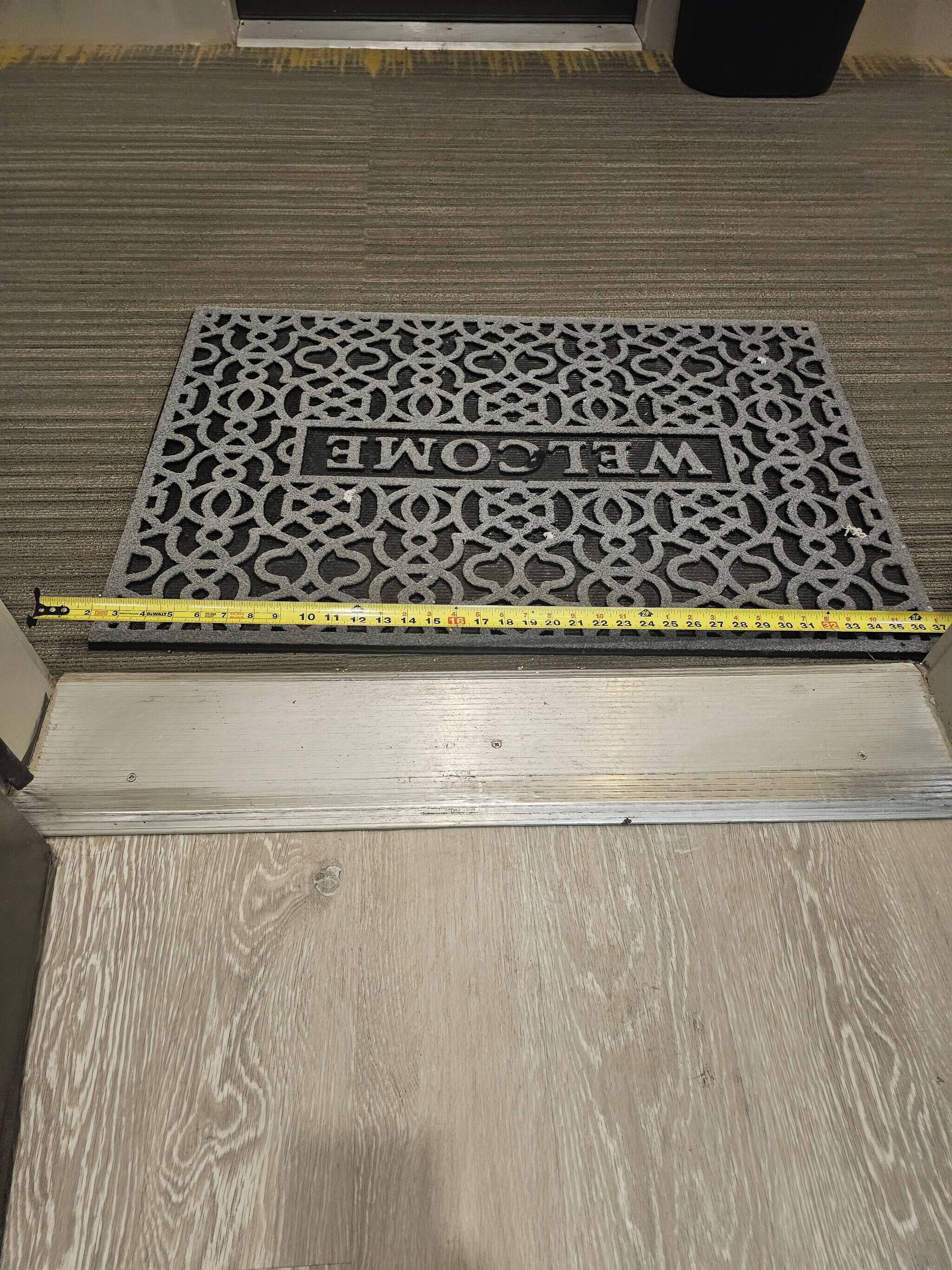 A welcome mat with a geometric pattern and the text 'WELCOME' on a wooden floor.