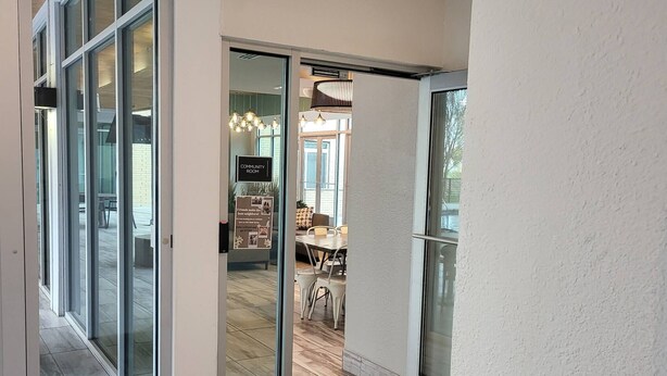 Ein modernes Interieur mit Glastür zu einem Essbereich, einem Schild für den Gemeinschaftsraum und einem Deckenventilator.