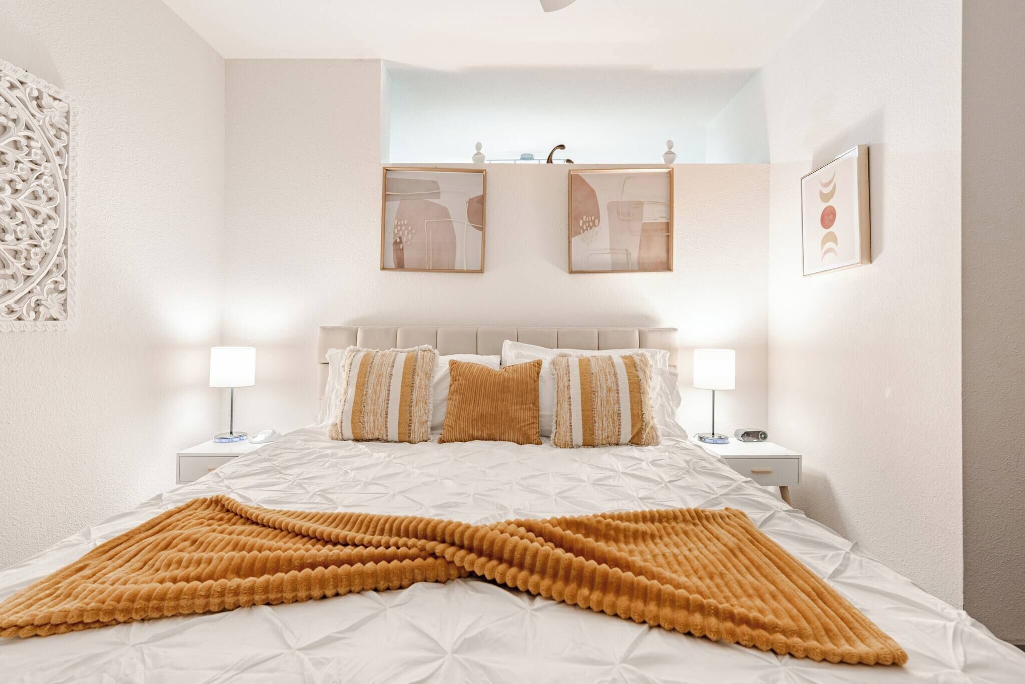 Een keurig opgemaakt slaapkamer met een bed, twee nachtkastjes en een kunstwerk aan de muur.
