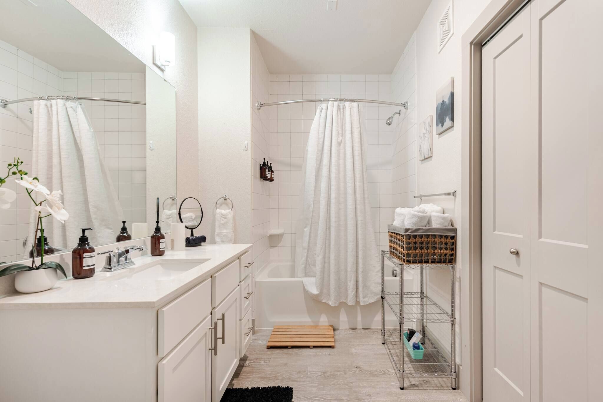 A modern bathroom with a shower, a sink with toiletries, and a mirror.