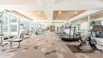 A gym with cardio machines, weight equipment, and large windows.