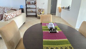 Un salon moderne avec une table à manger ronde, un canapé, une bibliothèque et une porte.