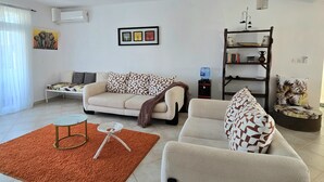 Un salon comprenant un canapé, un fauteuil, une table basse et une bibliothèque.