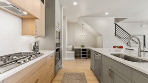 Eine moderne Küche mit eingebautem Herd, Backofen und Spüle, mit einer Treppe, die zu einer oberen Ebene führt.