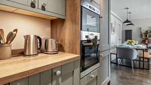 Eine moderne Küche mit Edelstahlgeräten, Holz Arbeitsplatten und einem Essbereich mit Tisch und Stühlen.
