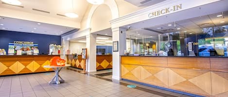A hotel lobby with a check-in counter, a concierge desk, and a seating area.
