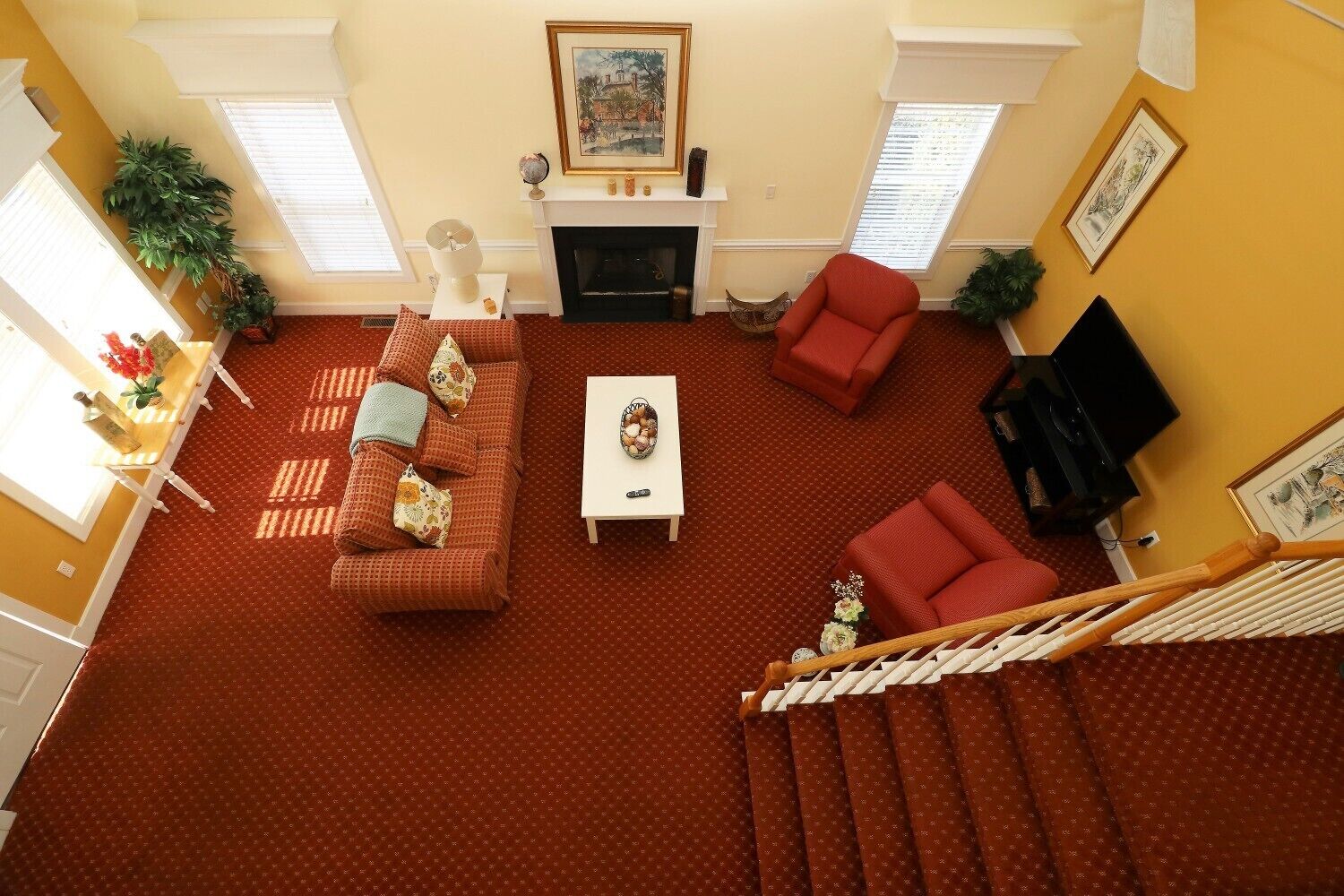 A living room with a sofa, armchair, coffee table, fireplace, and a staircase.