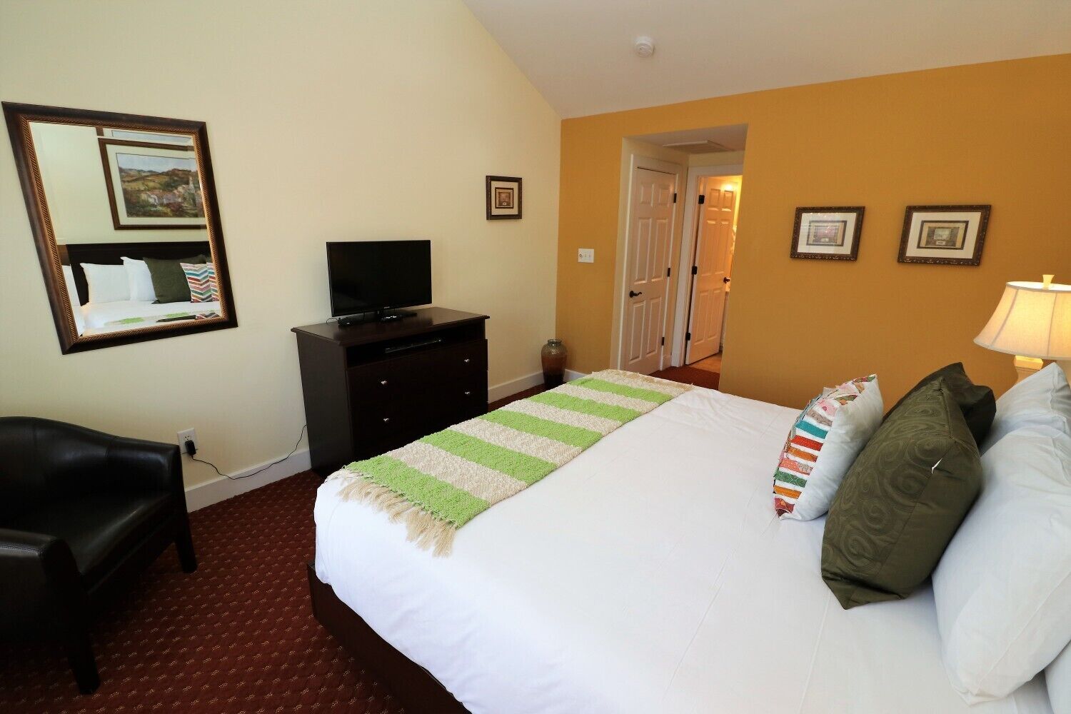 A hotel room with a bed, a TV on a dresser, a desk, and a chair.