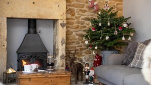 En hyggelig stue med en pejs af sten, et juletræ og en sofa.
