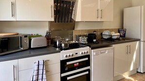 Una cocina moderna con armarios blancos, estufa, microondas y lavavajillas.