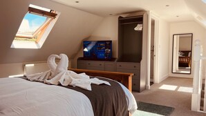 Un dormitorio con cama, televisión, armario y tragaluz.
