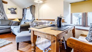Una sala de estar acogedora con una mesa de comedor de madera, un sofá gris y una lámpara.