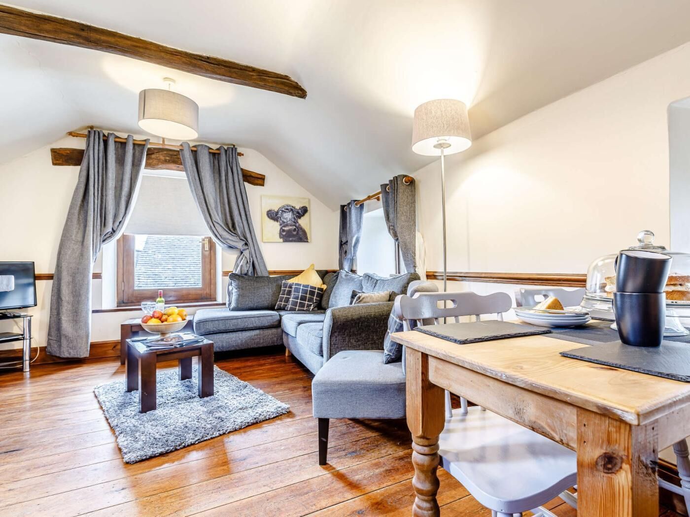 A cozy living room with a sofa, a coffee table, a dining table, and a lamp.