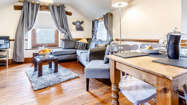 Una sala de estar acogedora con un sofá, una mesa de centro, una mesa de comedor y una lámpara.