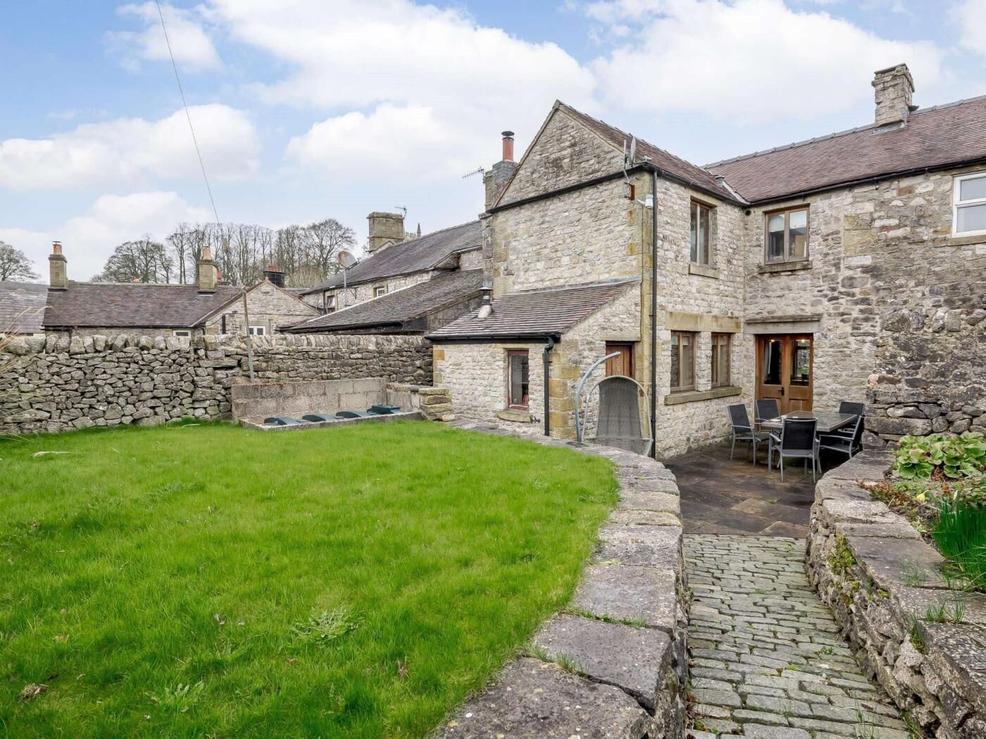 A stone building with a grassy yard and a patio area.