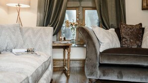 Un salon chaleureux avec deux canapés, une lampe, une petite table et une fenêtre avec des rideaux.