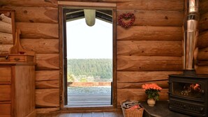 Ein rustikales Holzhaus-Interieur mit Holztür, Kamin, Korbwäsche und Blumen in einer Vase.