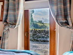 Ein Zimmer mit einer Holztür, die zu einer Steinsäule und einem Kiesweg führt.