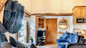 Ein gemütliches Wohnzimmer mit einer Couch, einem Fernseher und einer Küchenzeile mit Holzschränken und einer Mikrowelle.