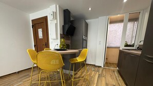 Een kleine keuken met een eethoek, houten vloeren en gele stoelen.