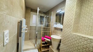Een moderne badkamer met een douchecabine van glas, een houten vloer en een wit wastafelmeubel.