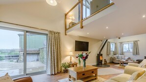 A spacious living area with a sofa, a coffee table, a TV, and a fireplace. - 4 Bed in Carnforth (oc-54457) (Burrow-with-Burrow)