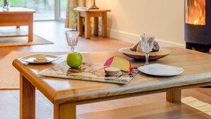 A wooden table with a plate of food, a glass, and a fruit. - 4 Bed in Carnforth (oc-54457) (Burrow-with-Burrow)