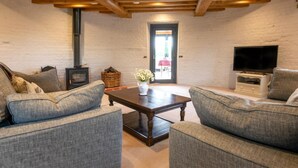 Una sala de estar acogedora con chimenea, dos sofás grises, una mesa de centro de madera y un televisor.