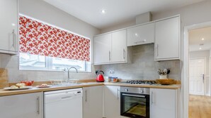 Eine moderne Küche mit weißen Schränken, einem Geschirrspüler, einem Herd und einem Backofen.