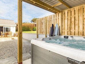 A hot tub under a wooden pergola with a view of a patio area and a house in the background. - 4 Bed in Bideford (oc-54448) (Appledore)