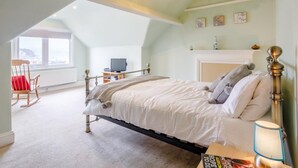 A bedroom with a bed, a rocking chair, a fireplace, and a television. - 3 Bed in Brixham (oc-bx001) (Brixham)