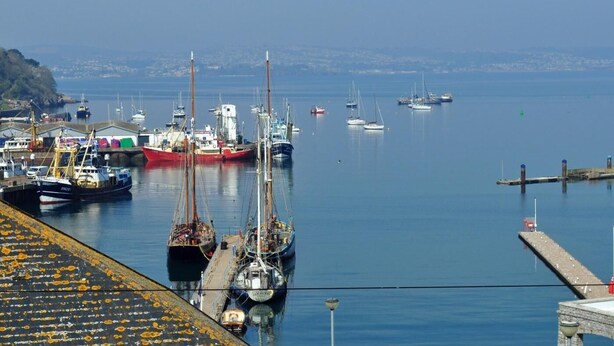 A harbor with boats docked, a pier, and a distant shoreline. - 3 Bed in Brixham (oc-bx001) (Brixham)