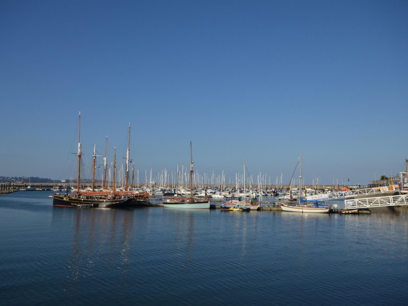 Una marina con numerose imbarcazioni ormeggiate, acqua calma e cielo sereno.