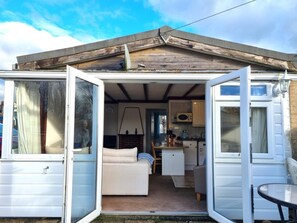 A compact, open-plan living space with a kitchenette, a sofa, and a dining area. - 2 Bed in Galmpton (oc-bx008) (Galmpton)