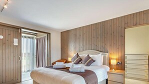 Ein Schlafzimmer mit einem großen Bett, Holzwandverkleidung, einem Nachttisch und einem Kleiderschrank.