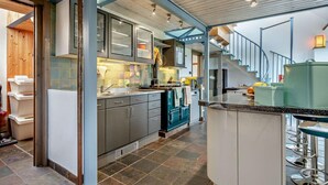 Eine moderne Küche mit einer zentralen Kochinsel, eingebauten Schränken und einer Treppe, die in eine obere Etage führt.