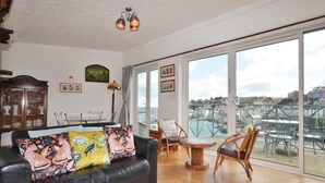 Ein geräumiges Wohnzimmer mit einer schwarzen Ledersofa, Holzboden und einem großen Fenster mit Blick auf die Stadt.