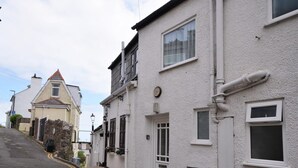 Eine enge Straße mit weißen Häusern, einer sichtbaren Tür und einem kleinen Fenster.