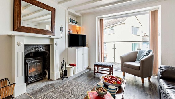Een woonkamer met een open haard, een bank, een televisie en een groot raam.