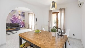 Ein modernes Wohnzimmer mit einer Couch, einem Esstisch mit Äpfeln und einem großen floralen Wandbild.