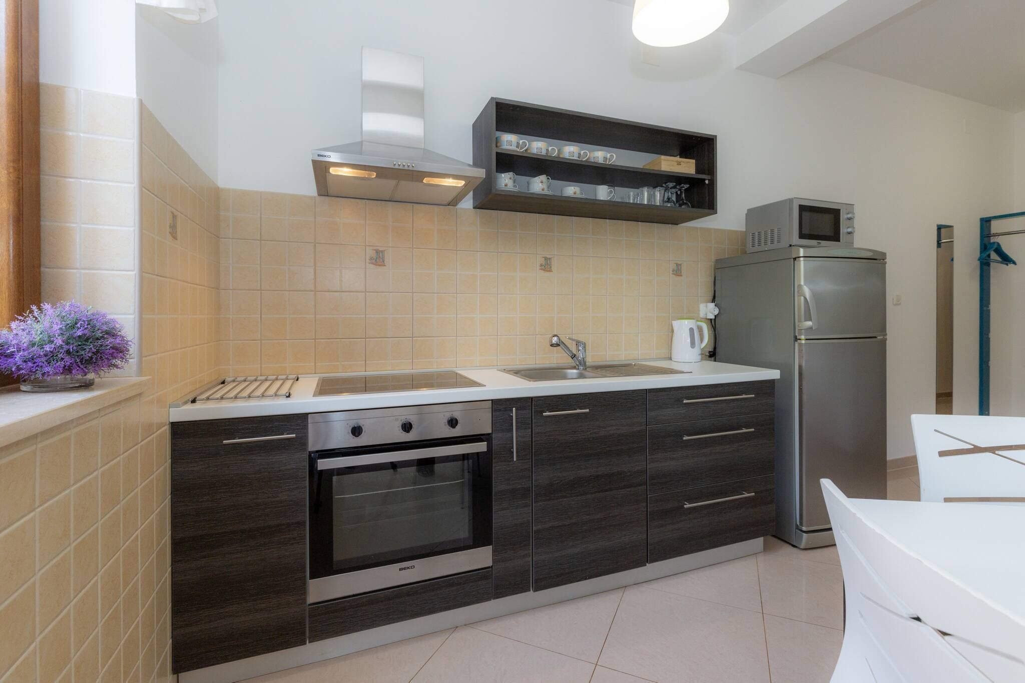Una cocina moderna con horno empotrado, microondas y refrigerador de acero inoxidable.