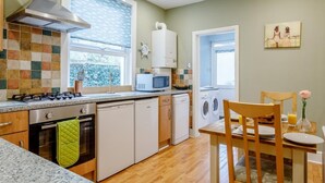 Una cocina moderna con estufa a gas, horno, microondas y lavadora.