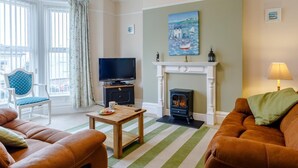 Una sala de estar con chimenea, televisor, sofá, sillón y un cuadro en la pared.