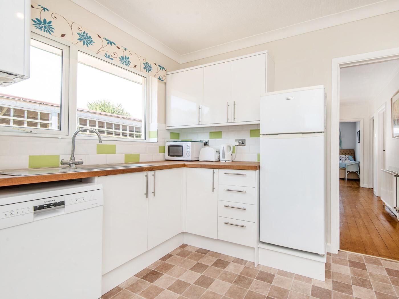 A modern kitchen with white cabinets, a built-in dishwasher, a microwave, and a refrigerator.