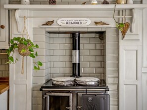 A kitchen with a white tiled wall, a black stove, and a welcome sign above the stove. - 1 Bed in Brixham (oc-bx036) (Brixham)