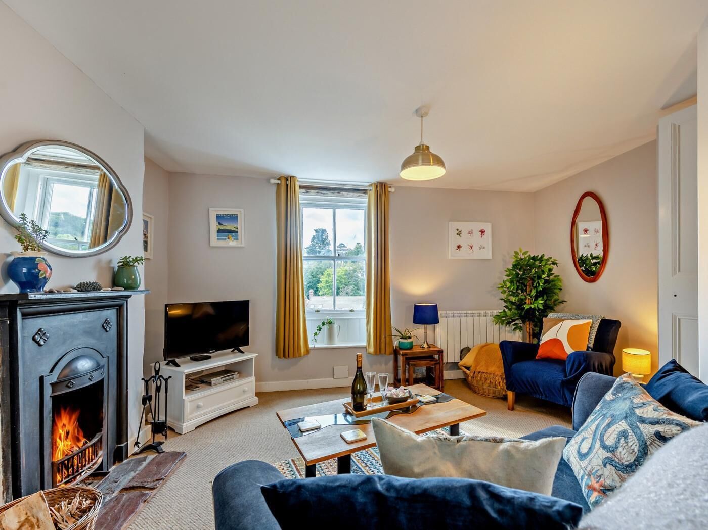 Un salon avec une cheminée, un canapé, un téléviseur et une vue par la fenêtre.